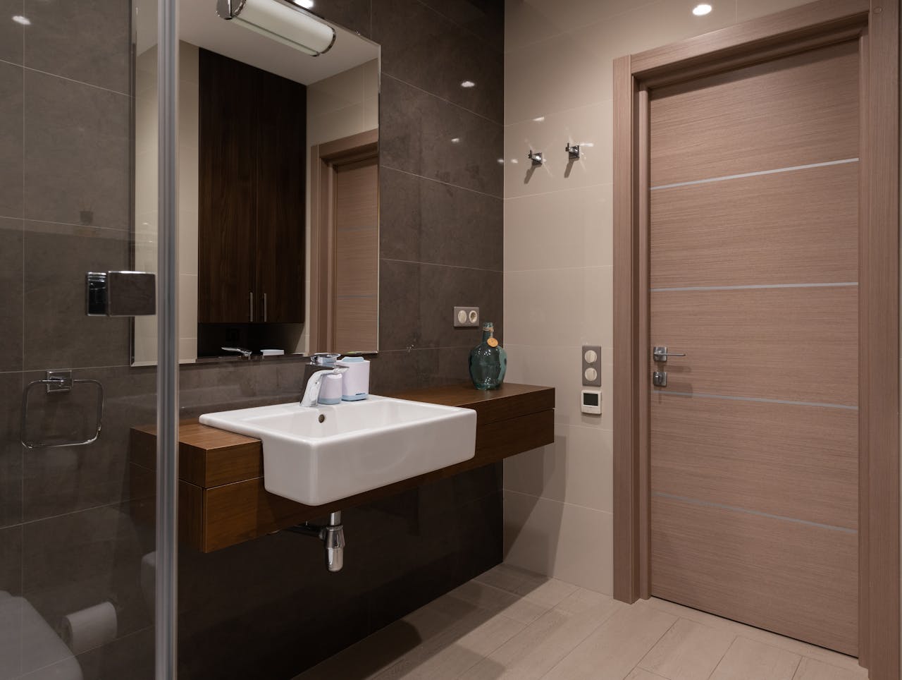 Sleek bathroom interior with a modern sink, mirror, and wooden door. Minimalist design focus.